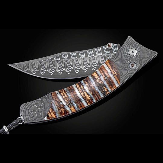 William Henry Knife
Knife Frame Type: 'Twist' damascus steel
Frame Engraver: Chad Nichols
Blade Type: 'Wave' damascus steel with an extra strong core of VG-10
Scale/Inlay: 10,000 year-old fossil Woolly Mammoth tooth
Number: 001/250
Gemstones/Embelli